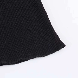 Detailed macro view of black ribbed knit fabric showing vertical textures and rolled edges