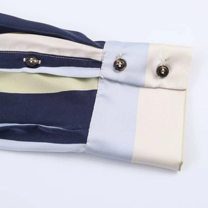 Detailed close-up of striped satin shirt cuffs featuring double amber button closures