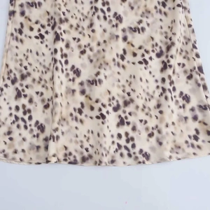 Detail of satin midi skirt fabric showing smooth texture and leopard animal print