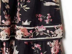 Detailed close-up of floral print on black woven fabric with layered ruffle hem details