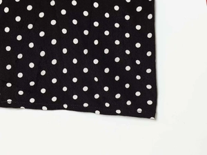 Close-up of black fabric with white polka dot pattern and smooth textile texture