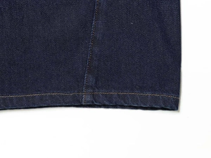 Detailed close-up of high-quality yellow stitching on deep blue denim trousers