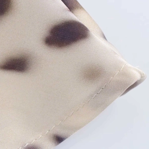 Detail of satin fabric showing smooth texture, irregular print, and neat stitching work