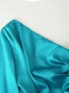 Close-up of teal satin fabric texture with elegant drapes and glossy smooth finish