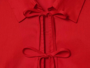Detail of red shirt collar with minimalist bow-tie straps and smooth cotton texture