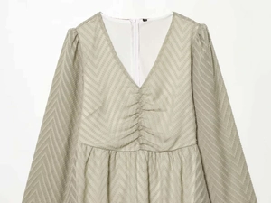Detailed view of the V-neckline and textured pleated fabric of the light green dress