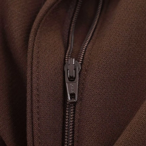 Dettaglio macro della cerniera in metallo e del tessuto twill sui pantaloni marrone scuro