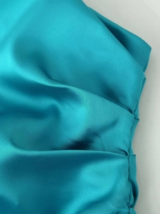 Macro shot of smooth lake blue satin fabric texture with elegant draping folds