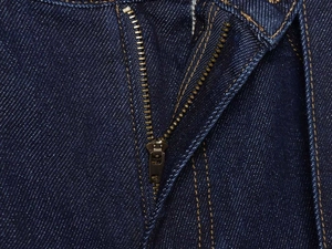 Detailed close-up of dark indigo denim jeans featuring metal zipper and yellow stitching