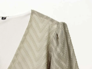 Detail of light green pleated dress with V-neckline and textured flocking dots fabric