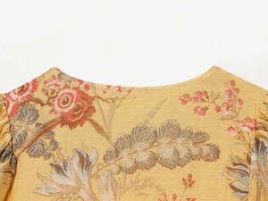 Detailed close-up of retro floral pattern and neckline on yellow puff sleeve blouse