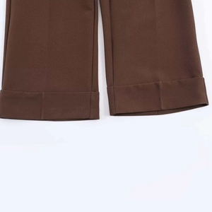 Dettaglio dei pantaloni a gamba larga marrone scuro con risvolto e pieghe stirate eleganti
