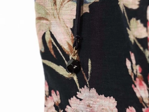 Detail view of floral print fabric with black drawstring and beaded metal pendant