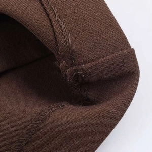 Dettaglio macro della cucitura interna overlock sui pantaloni a gamba larga marrone scuro