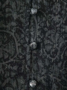 Détail de la robe à col en V avec fils métalliques et boutons recouverts de tissu