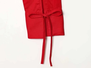 Detailed close-up of a vibrant red blouse sleeve featuring a minimalist bow tie design