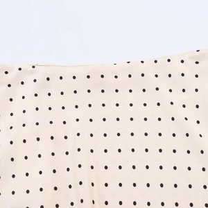 Detailed macro shot of black polka dot pattern on light beige satin fabric texture