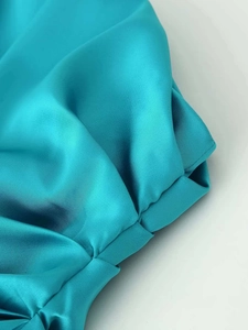 Close-up of the elegant peacock blue satin fabric with fine pleated ruffles and texture