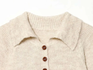 Detail of cream knit polo collar showing texture and brown tortoiseshell buttons