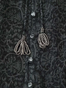 Détail de robe à col en V avec imprimé paisley, fils métallisés argentés et pompons