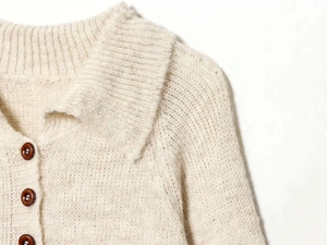 Detailed close-up of quilted knit cardigan collar with textured amber-style buttons