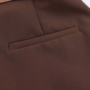 Dettaglio macro dei pantaloni larghi marroni di alta qualità con tasca a filetto e tessuto fine