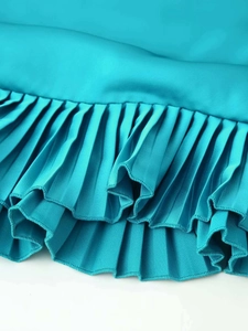 Detail of teal satin fabric with dense accordion pleats and elegant wavy hem finish