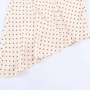 Close-up of cream polka dot satin fabric with a light texture and asymmetrical hem detail