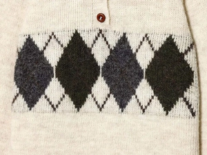Detailed close-up of knit texture with argyle diamond pattern and brown button