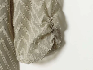 Detail of light green pleated sleeve cuff featuring unique clipped jacquard fabric texture