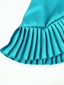 Detailed macro view of vibrant turquoise pleated satin fabric with elegant drape