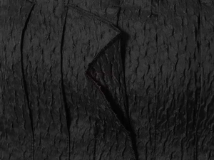 Detailed macro view of charcoal black wrinkled texture fabric with pleated craftsmanship
