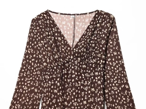 Detailed view of deep V-neckline and pleated floral fabric texture on brown dress