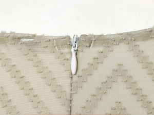 Detail of invisible zipper closure and textured wave jacquard fabric on the light apricot dress