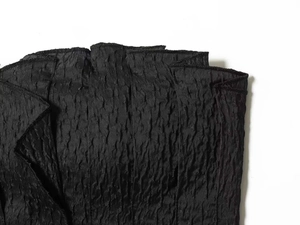 Detailed view of black textured fabric with 3D polka dots and refined stitching quality