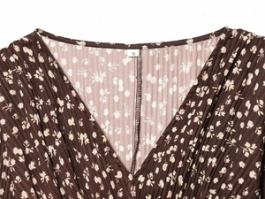 Detail of V-neckline on pleated brown floral dress with S size label and fabric texture