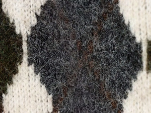 Macro shot of black and white argyle knit sweater fabric with soft mohair texture