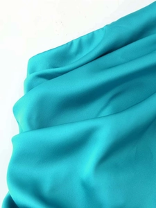 Detail of teal blue silk fabric showing smooth texture and elegant drape on the dress