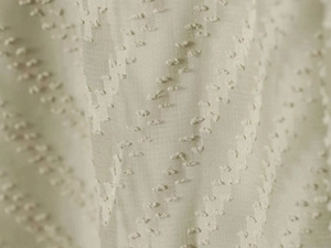 Close-up of beige pleated fabric with swiss dot pattern and sheer chiffon texture