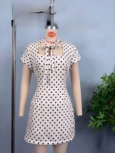 Detail of white mini dress with black polka dots, square neckline and front bow decoration