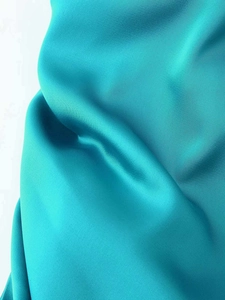 Detailed macro view of the glossy teal satin fabric with smooth drape and silk-like texture