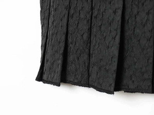 Close-up of charcoal black pleated fabric texture showing vertical folds and stitching