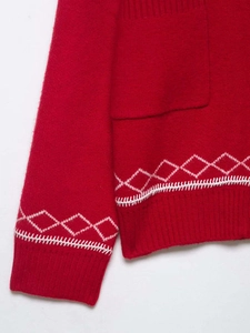Détail du cardigan en maille rouge avec motifs de losanges roses et poignets côtelés