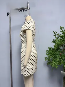 Detail view of the slim-fit white polka dot mini dress with a round neck and short sleeves
