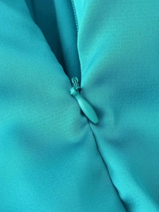 Detail shot of a teal fitted dress showing the high-quality invisible zipper and smooth fabric