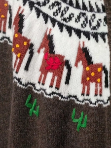 Détail macro du cardigan en maille Fair Isle avec jacquard de chevaux et texture laine