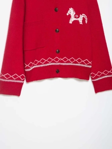 Détail du cardigan rouge en maille avec jacquard de cheval blanc et broderie losange