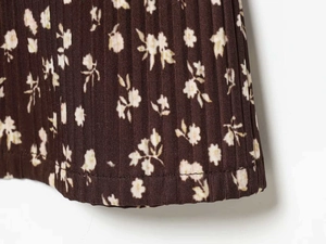 Detail of V-neck pleated dress featuring floral print and high-quality hem stitching