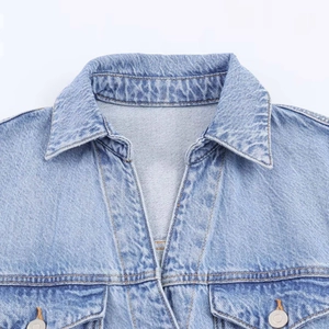 Detail of light blue denim dress showing classic collar and symmetrical chest pockets