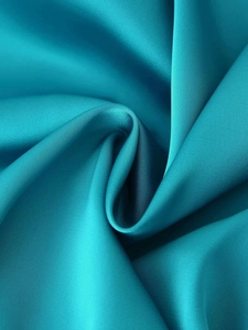 Detail of teal satin fabric with silky smooth texture and luxury draped silhouette
